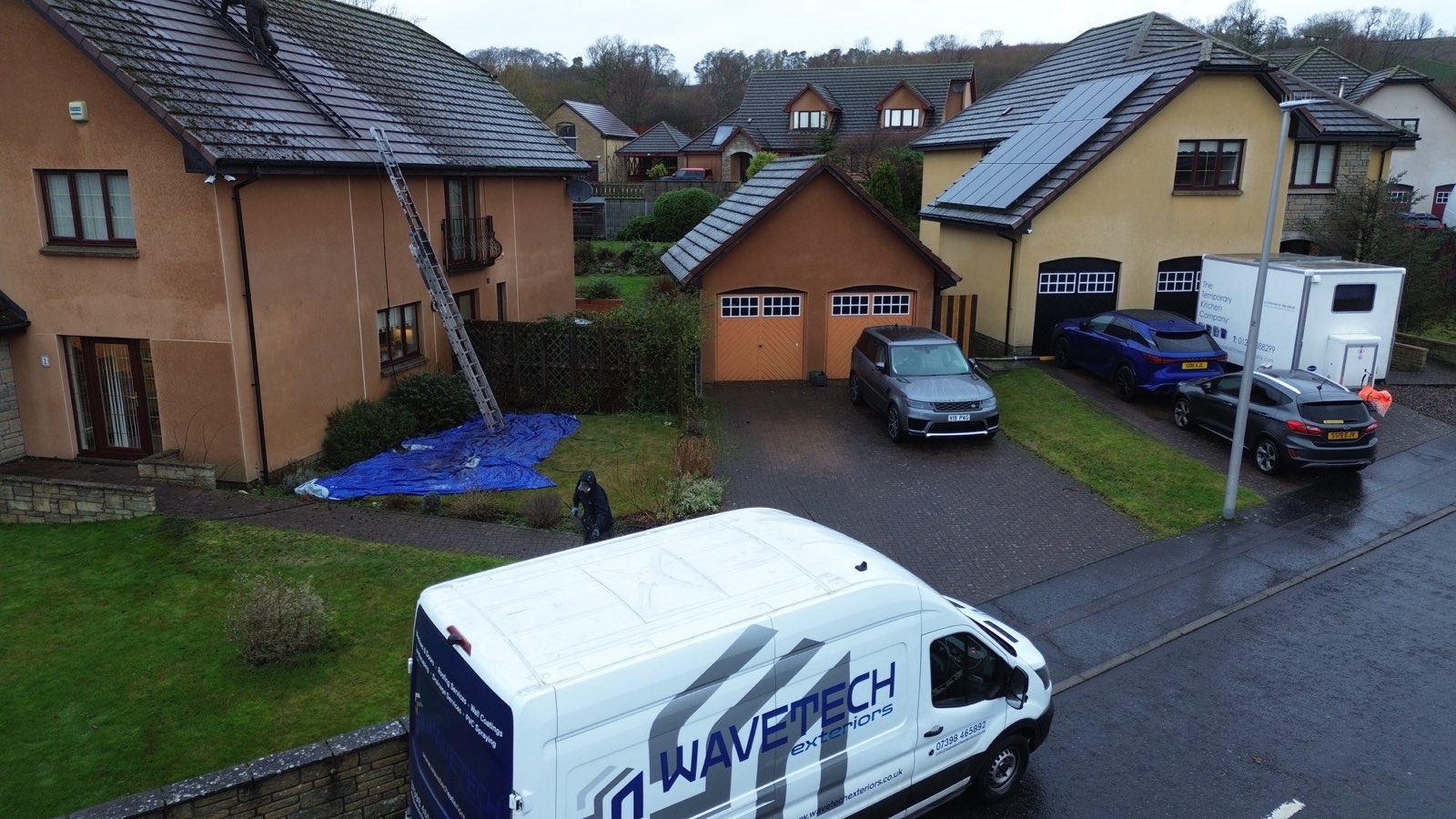 The WaveTech Exteriors van on a residential street while the local team works on nearby homes