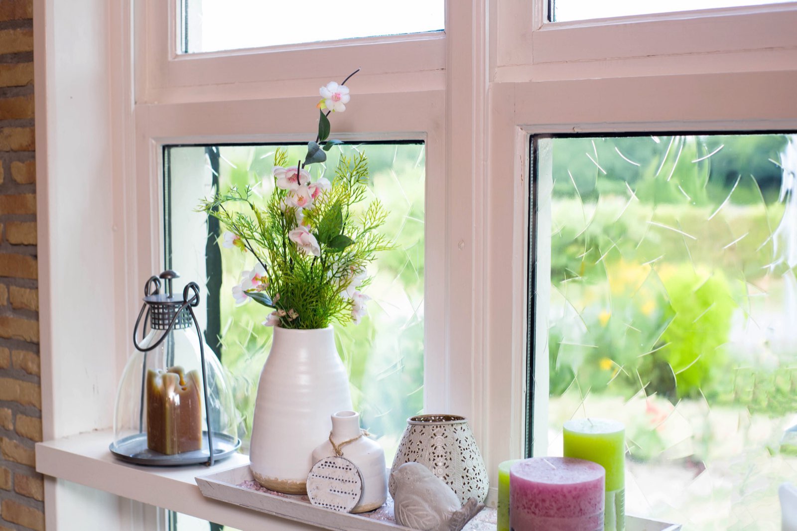 A bright uPVC window with a decorated sill looking out onto a garden